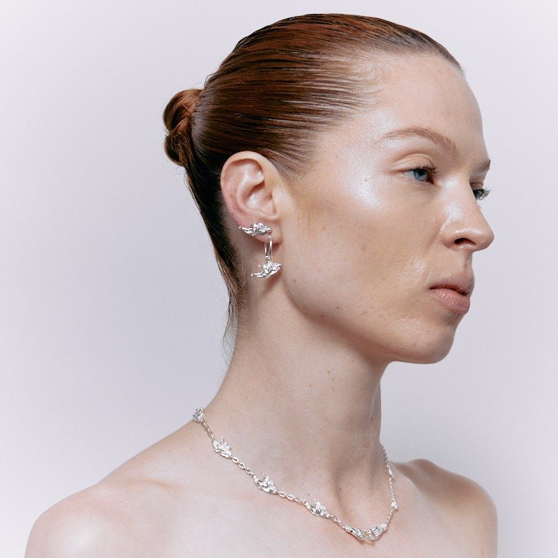 Woman with sleek bun hairstyle wearing a pair of sterling silver Botticini Hoops cherub earrings.