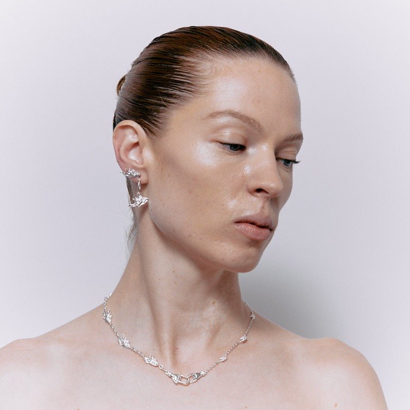 Profile of a woman with a polished bun wearing a pair of sterling silver Botticini Hoops angel earrings.